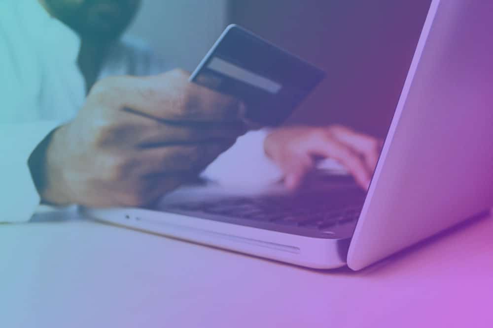 ecommerce-head a man holding a credit card and using a laptop