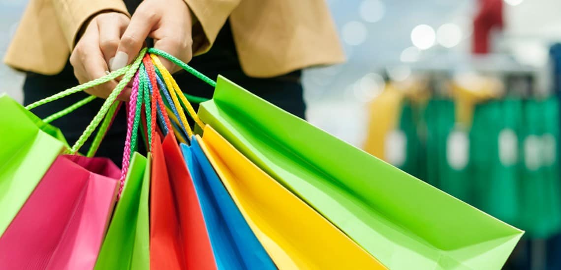 woman holding many different coloured bags