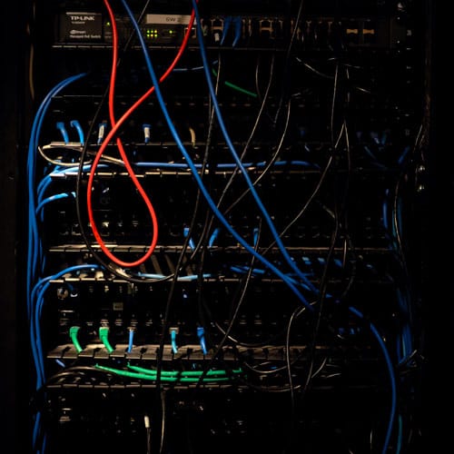 it-company-001 image of it infrastructure - many wires hanging from the back of a metal box